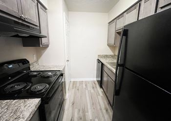 an empty kitchen with black appliances and wood flooring at Hunter Ridge Apartments, Cincinnati, Ohio